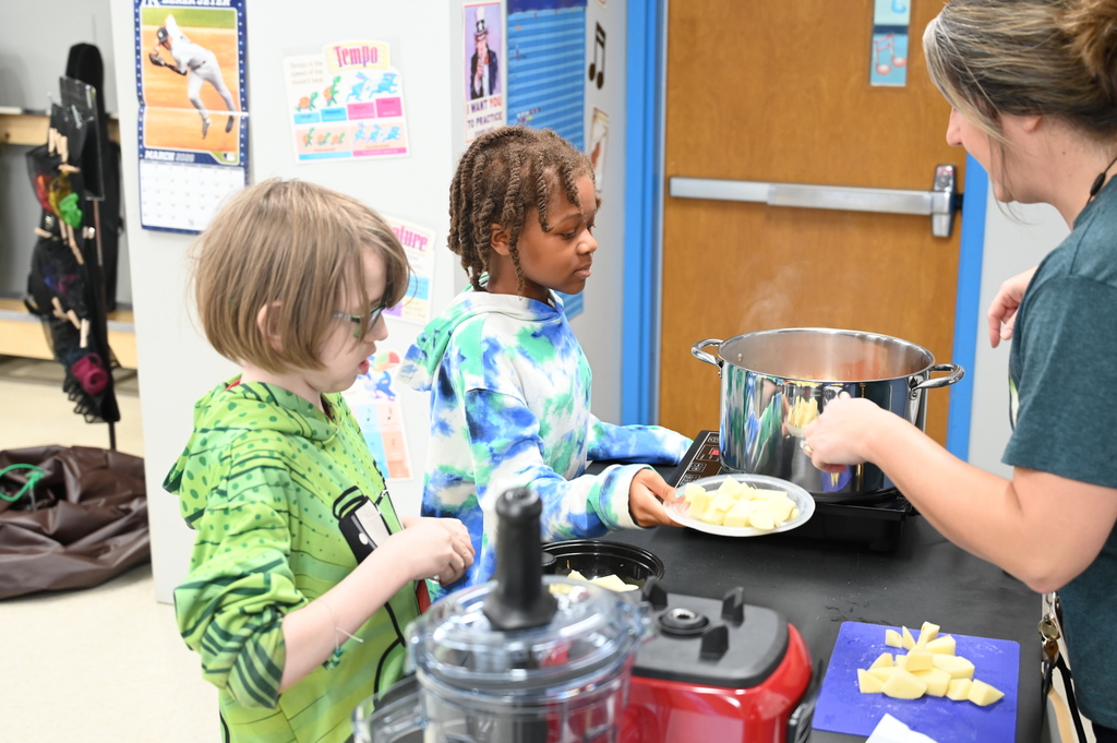 Students prepare to add vegetables to a steaming pot for soup.