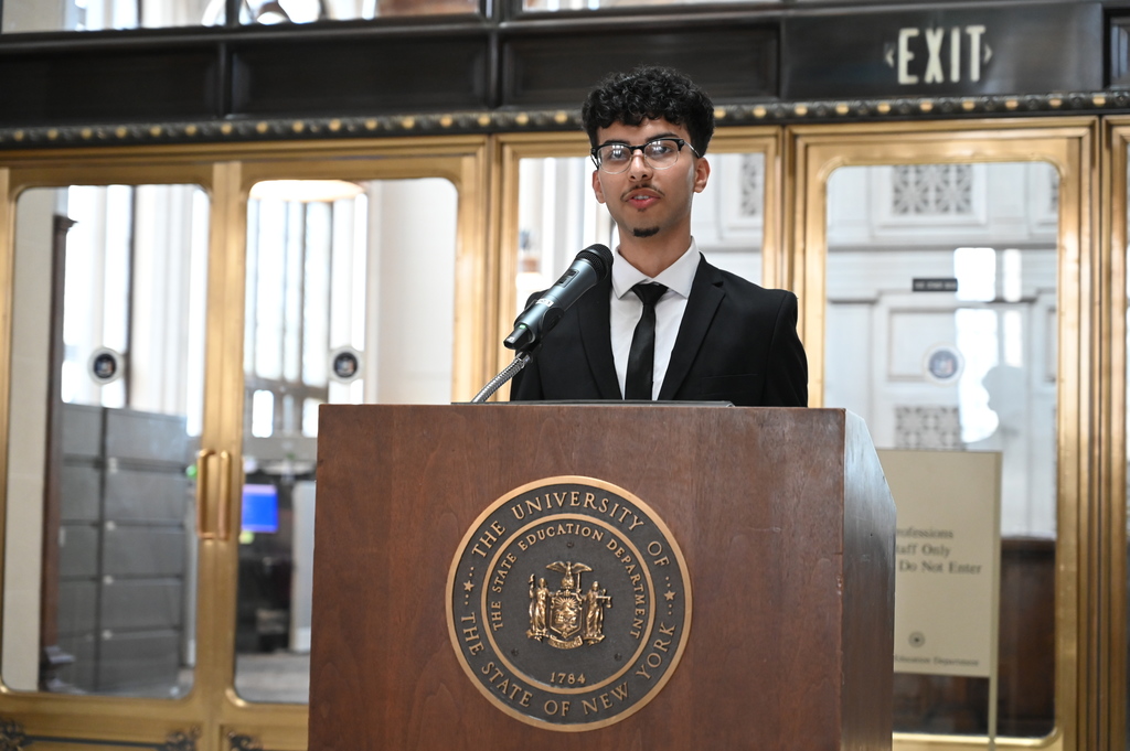 Shaker High School senior Nawaf Kassem stands at a podium, reading a proclamation.