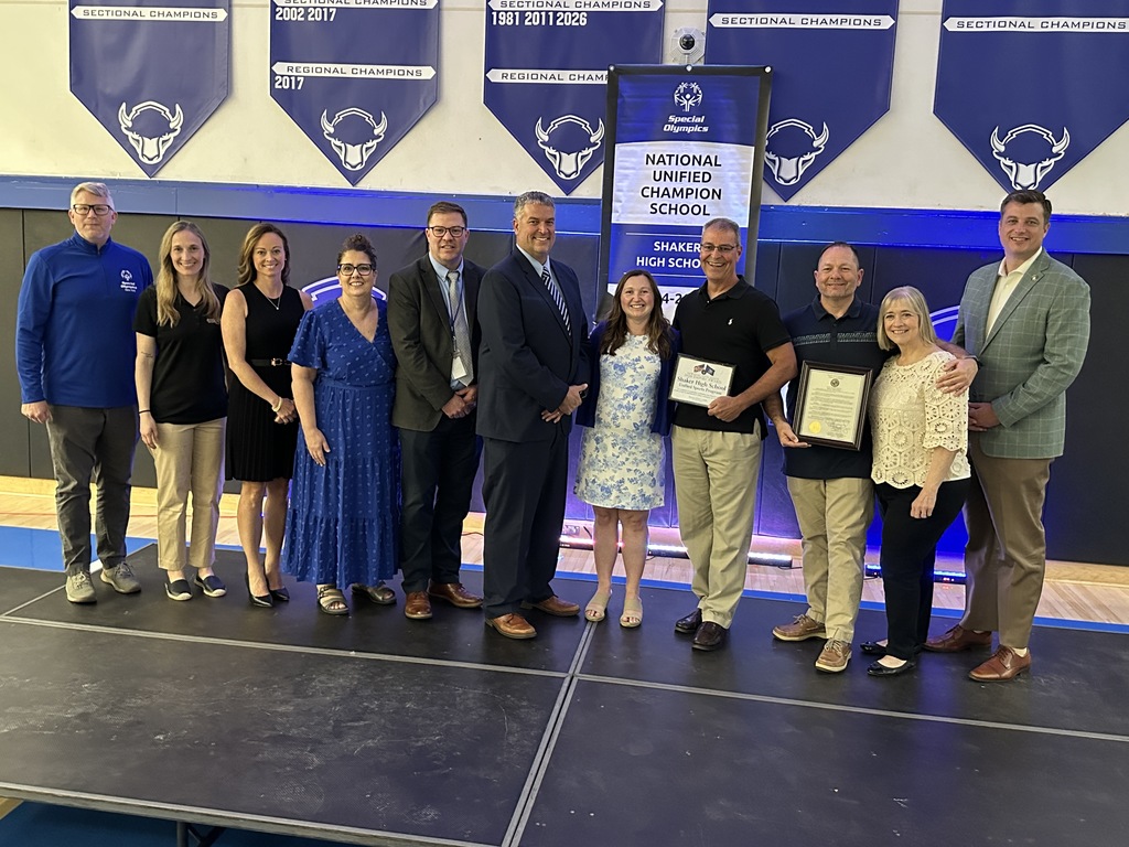 Unified coaches join administrators and representatives on stage to pose in front of the new banner.