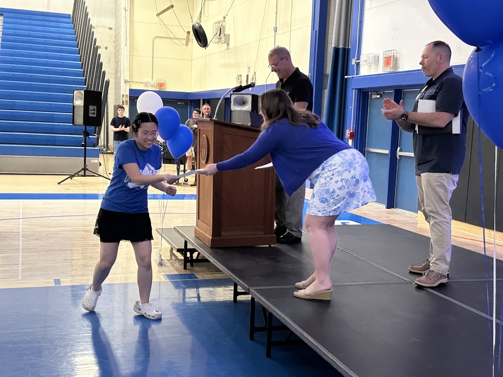 A teacher hands a student a certificate.