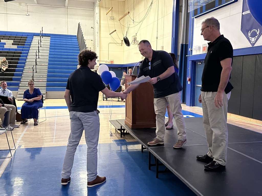 A coach shakes a student's hand as he hands him a certificate.