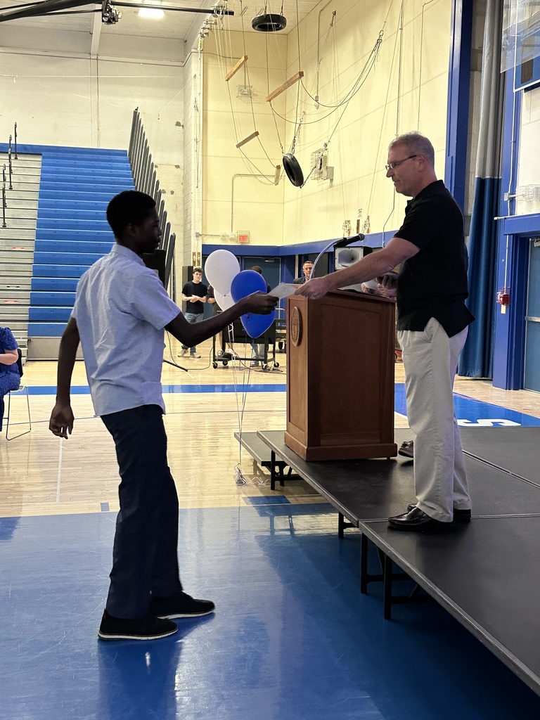 A coach hands a student a certificate.