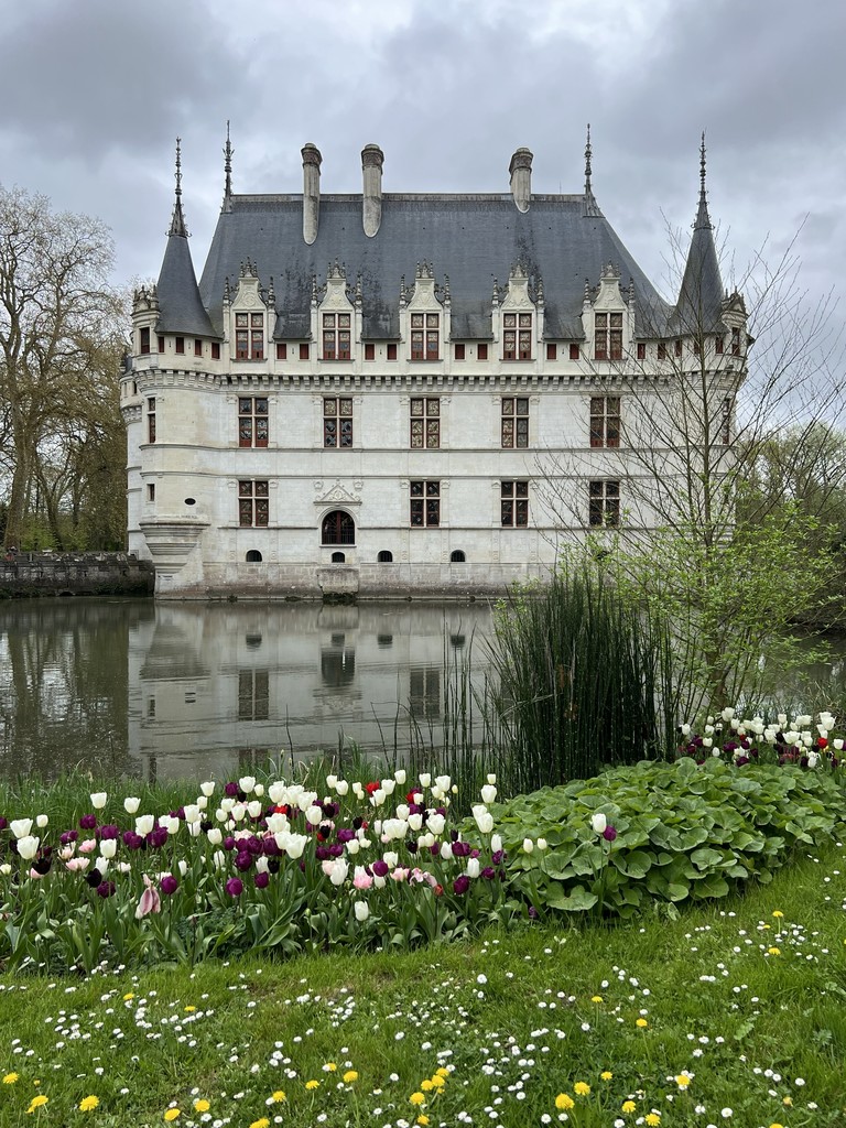 A large castle like building in France sits on a body of water.
