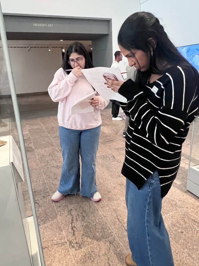 Students take notes inside a museum.