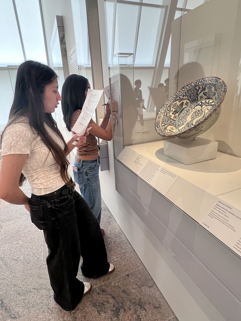 Students take notes as they look at an ancient artifact.