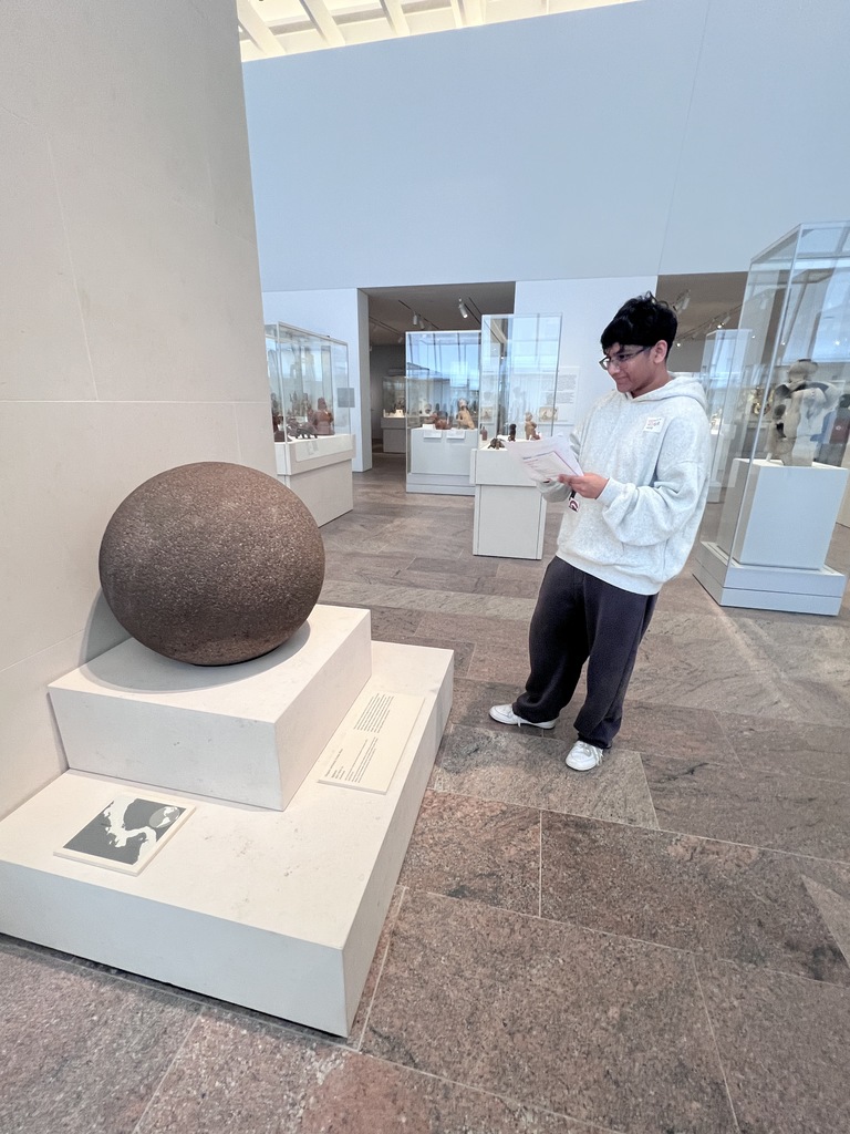 A student looks at a large sphere on a platform at the Met.