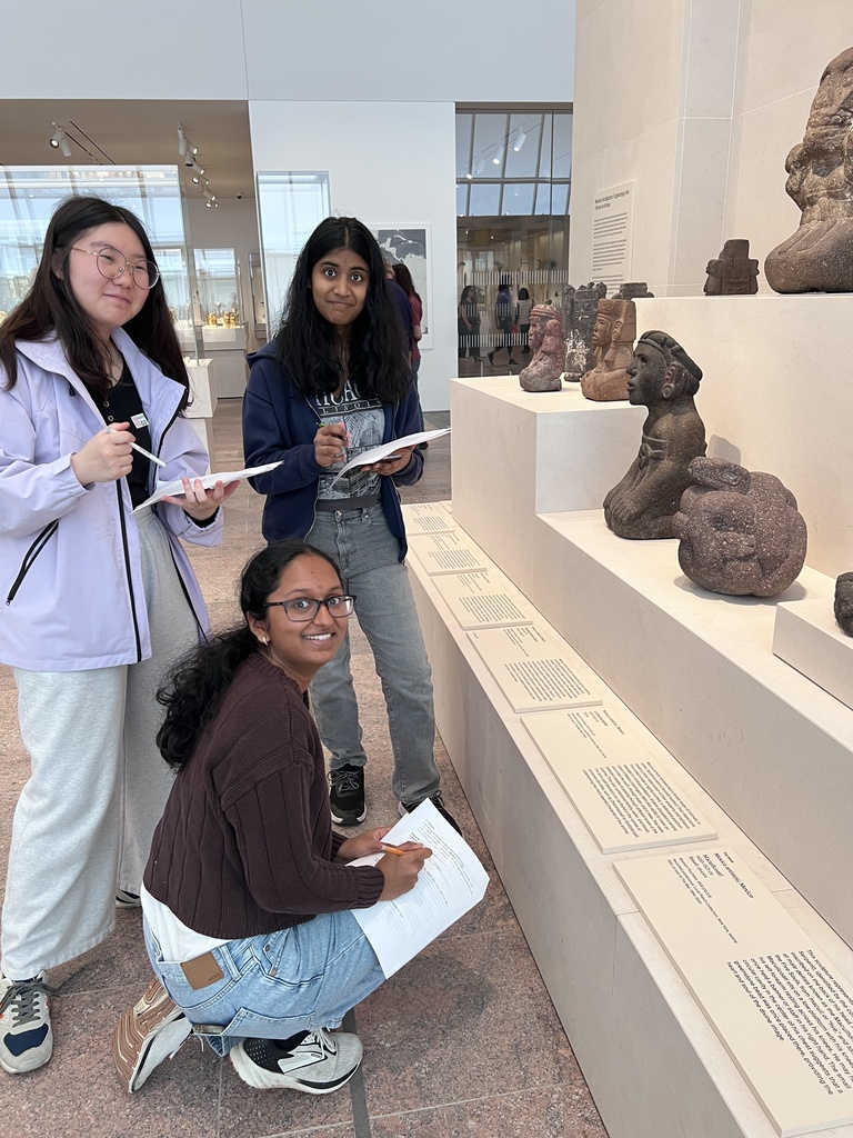 Students pose in front of ancient artifacts at the Met.