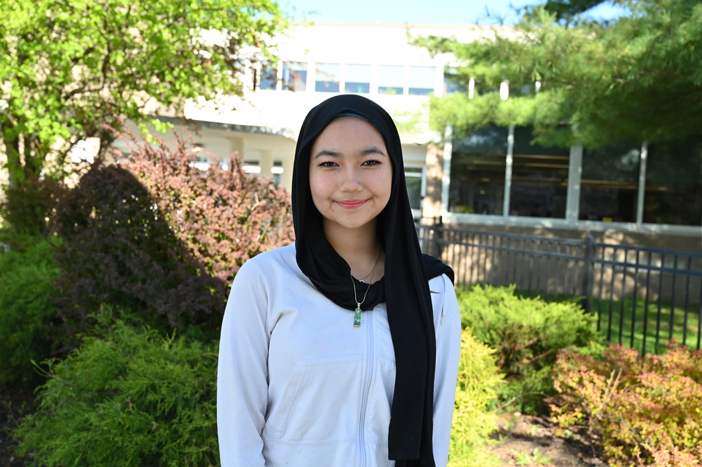 An image of the student who won best poem standing in front of greenery.