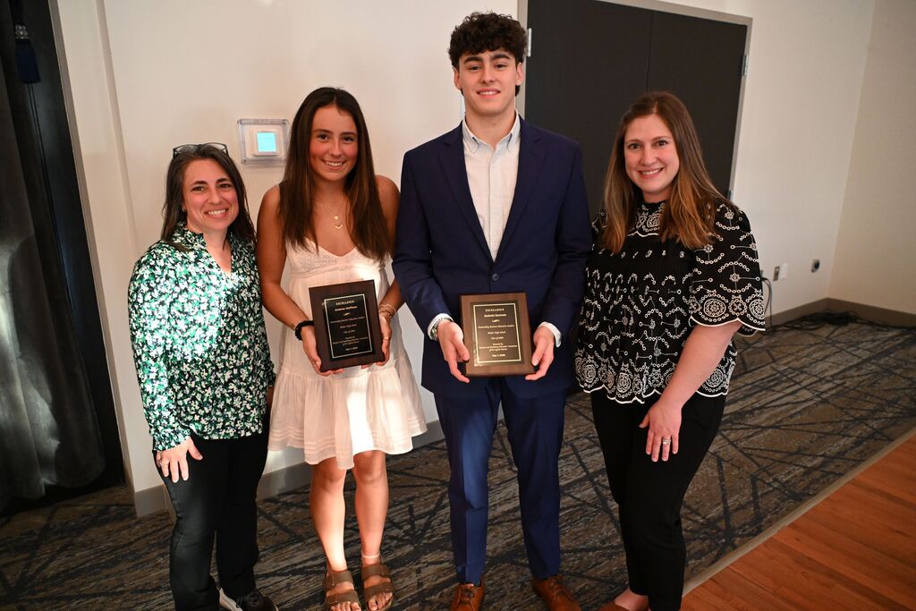 two students holding awards standing with teachers