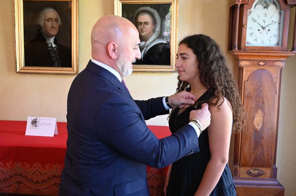 Joelle Hannoush's father pins her Daughters of the American Revolution pin on her dress during a ceremony.