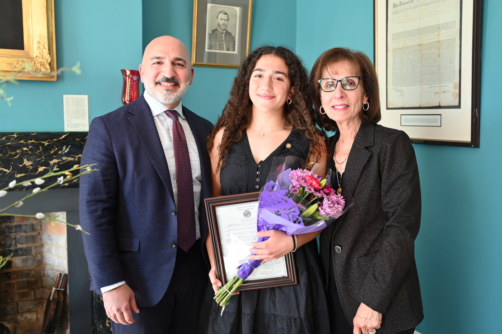 Daughters of the American Revolution Good Citizen Award recipient Joelle Hannoush poses with family members as she holds a plaque and flowers.