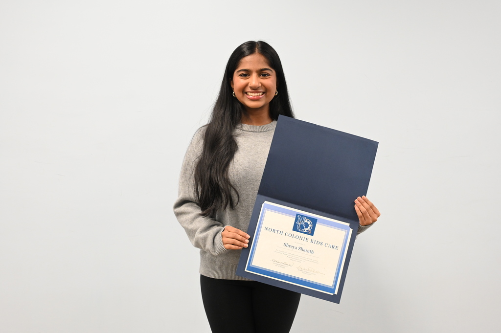 A student proudly shows off her certificate of recognition as a Kids Care recipient.