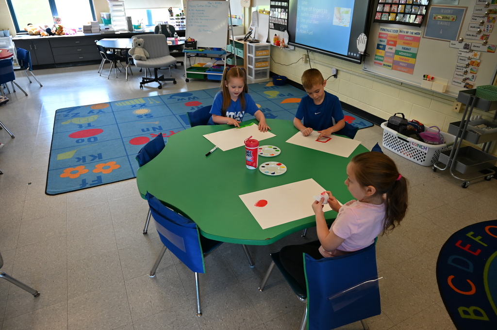 students sitting at a table doing artwork