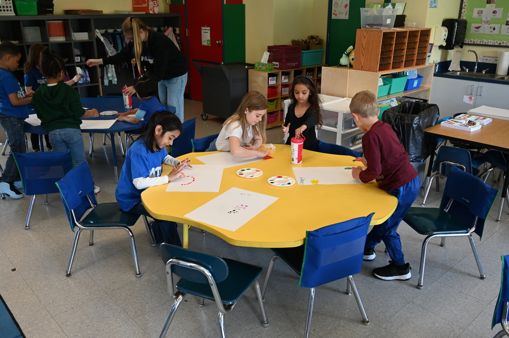 students sitting at a table doing artwork