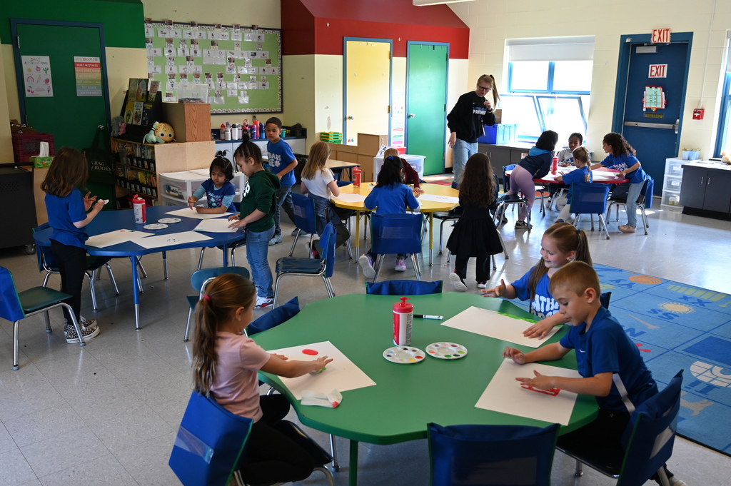 students sitting at a table doing artwork