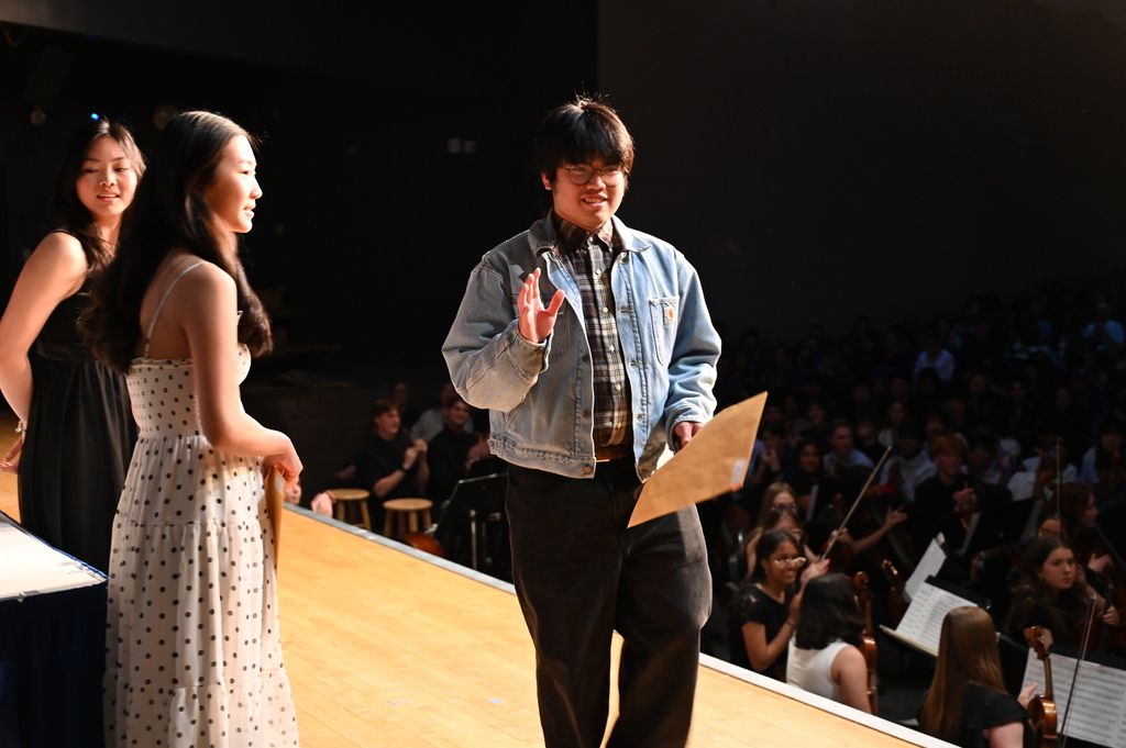 A student waves after accepting an award on stage.