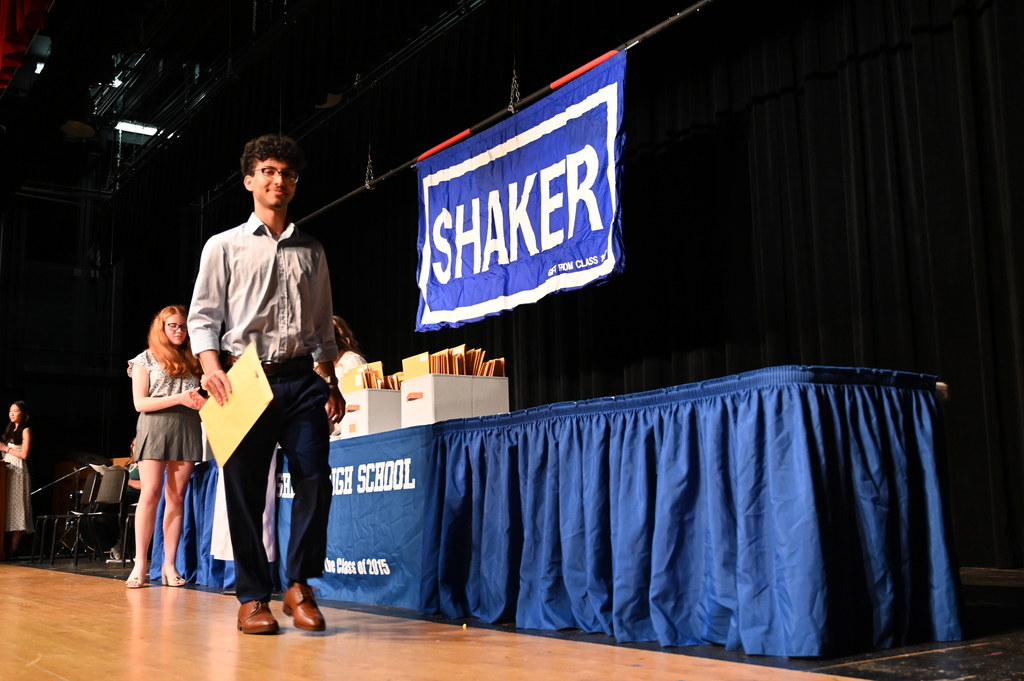 A student walks off the stage with an envelope after receiving an award.