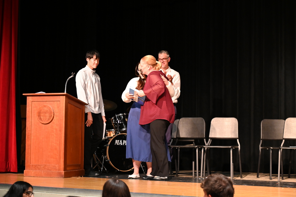 Mrs. Fox gets a hug from a student as she accepts the yearbook dedicated to her.