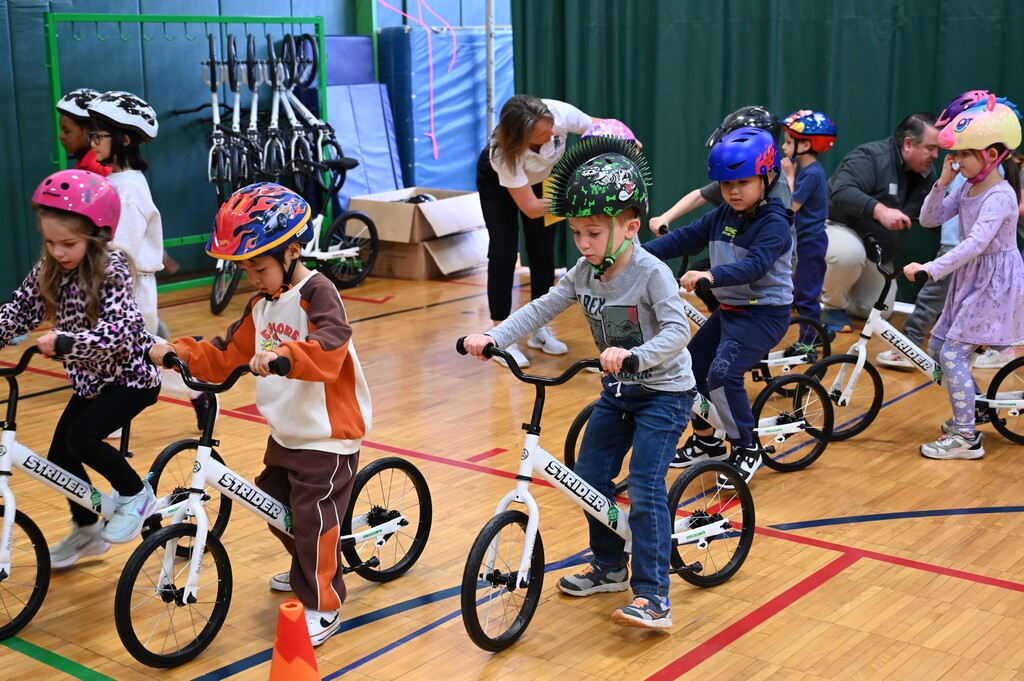 Students in helmets ride bikes together in physical education class.