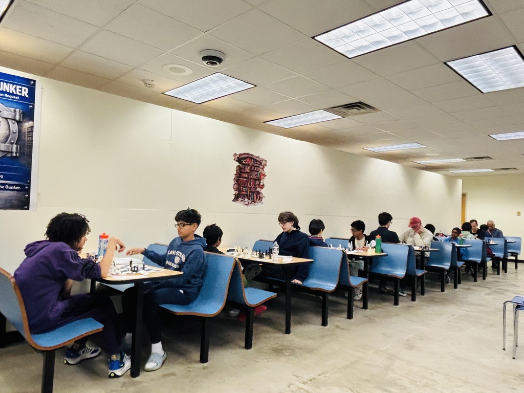 A long row of tables filled with people playing chess.