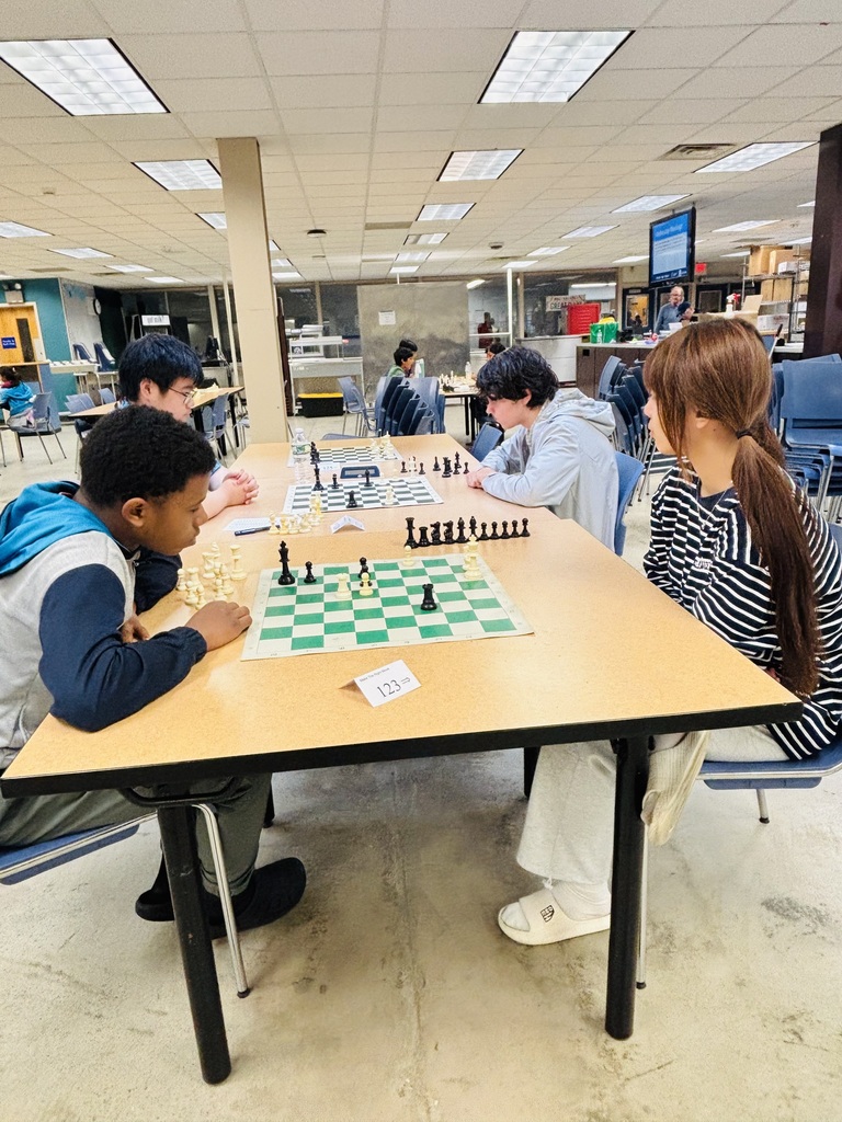 Two pairs of students, playing chess against one another.