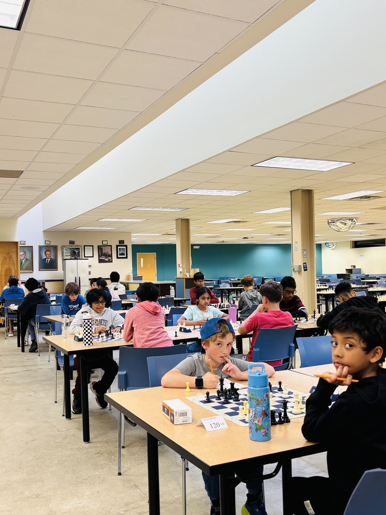 Students seated, playing chess throughout the cafeteria.