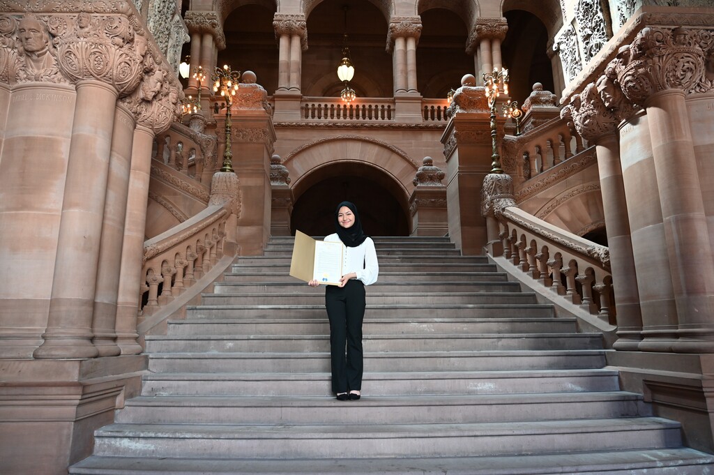 Sima poses with her state resolution on the Million Dollar Staircase.