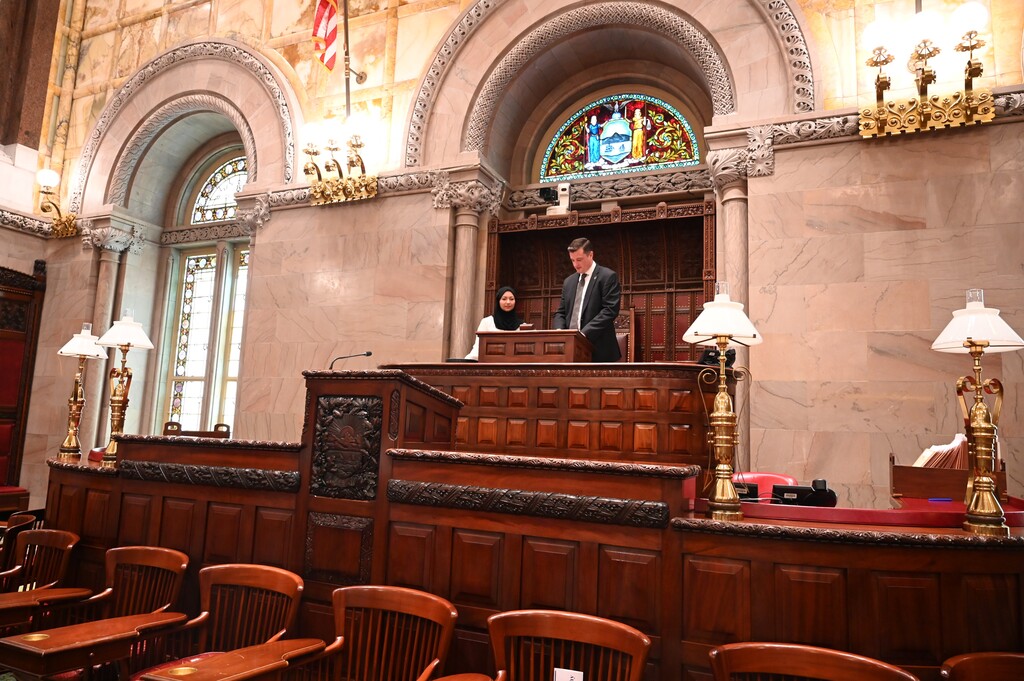 Senator Jake Ashby stands at the dais with Sima as part of the tour of the Senate chamber.