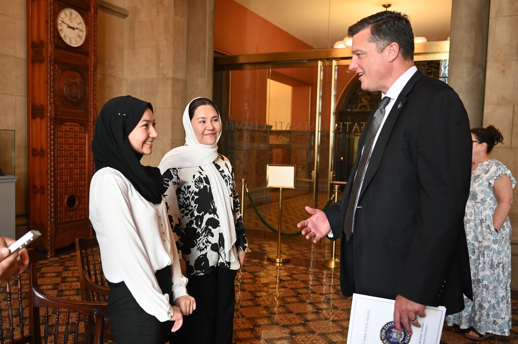 Senator Jake Ashby speaks to NYS Poetry Prize winner Sima Amiri and her family.