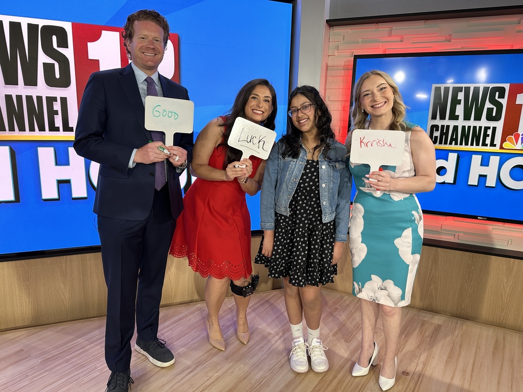 WNYT morning anchors hold signs reading "Good Luck Krrisha" as they pose with her.