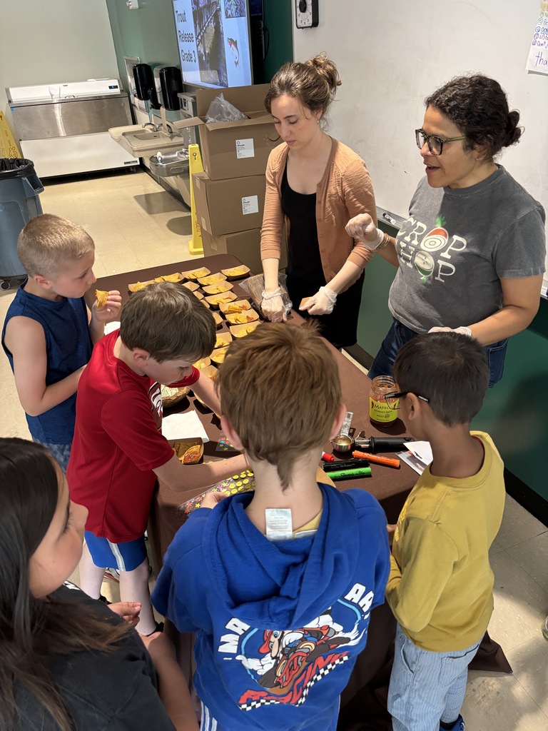 Students excitedly take samples of tortilla chips from a table.