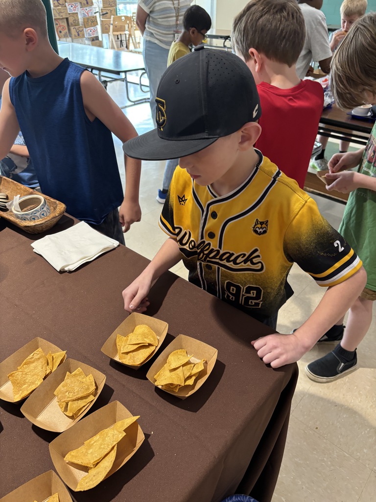 A student reaches for a sample of tortilla chips on a table.