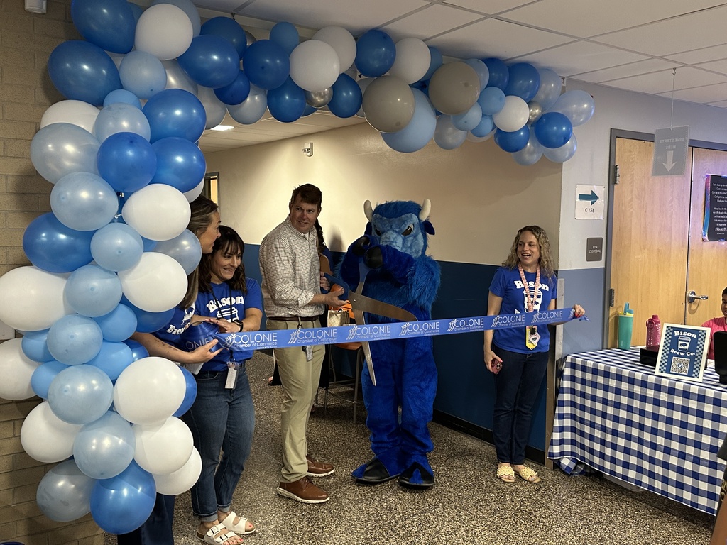 The Bison helps administrators cut a large ribbons with a big pair of shears.