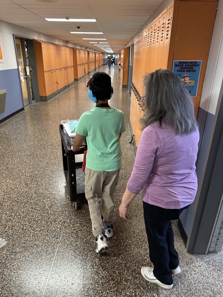 A student and faculty member use a cart to deliver goods from Bison Brew.