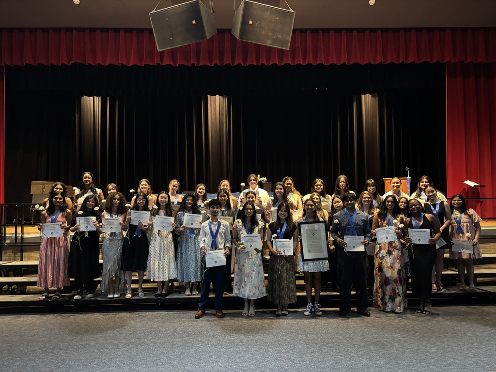 40 newly inducted members of the National English Honor Society pose on risers with certificates.