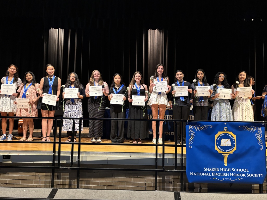 A dozen members of the NEHS induction class pose on stage with certificates.