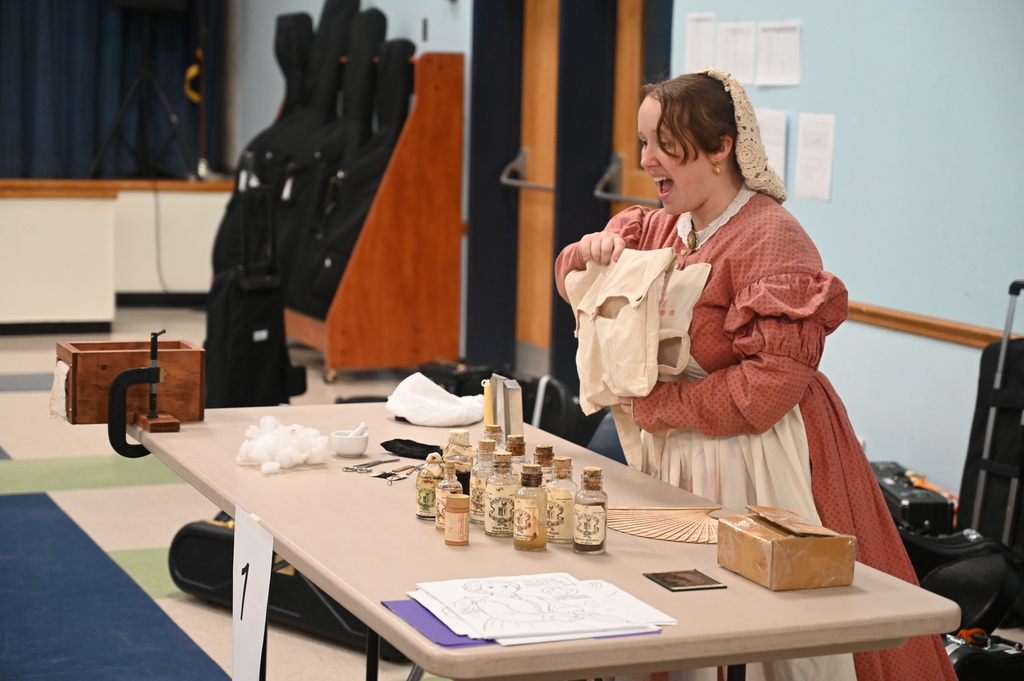 An actor portraying Clara Barton speaks from behind a table.