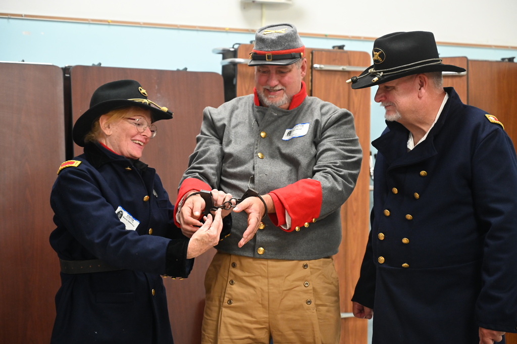 An actor portraying a provost removes handcuffs from a soldier.