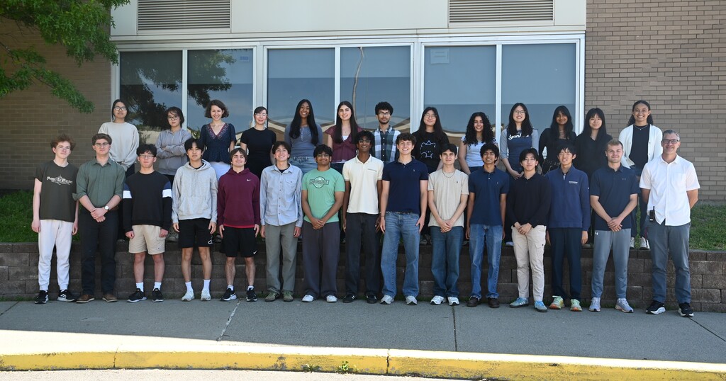 An image of students recognized as Honor Graduates posing alongside Shaker Principal Mr. Puccioni outside of the building.