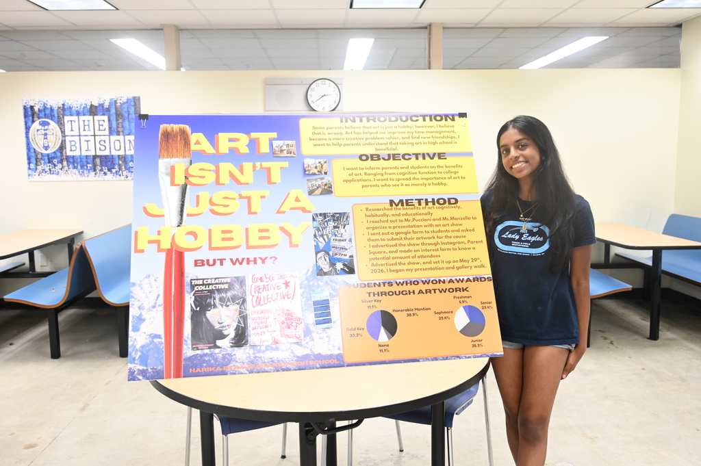 student posing with a sign stating art isn't just a hobby