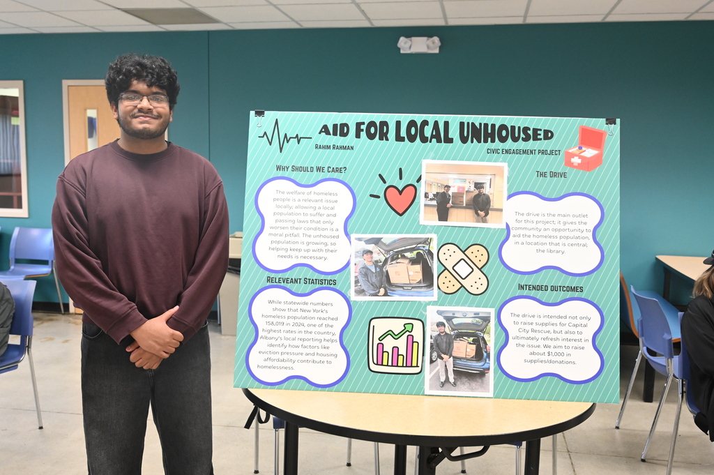 student posing with a sign stating aid for local unhoused