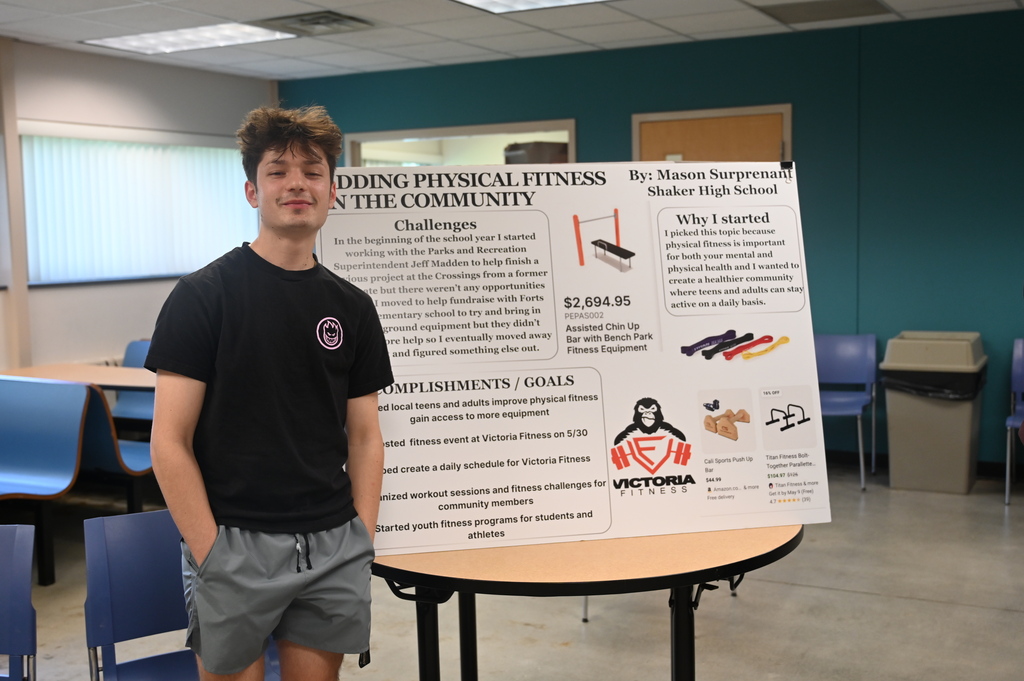 student posing with a sign stating adding physical fitness in the community