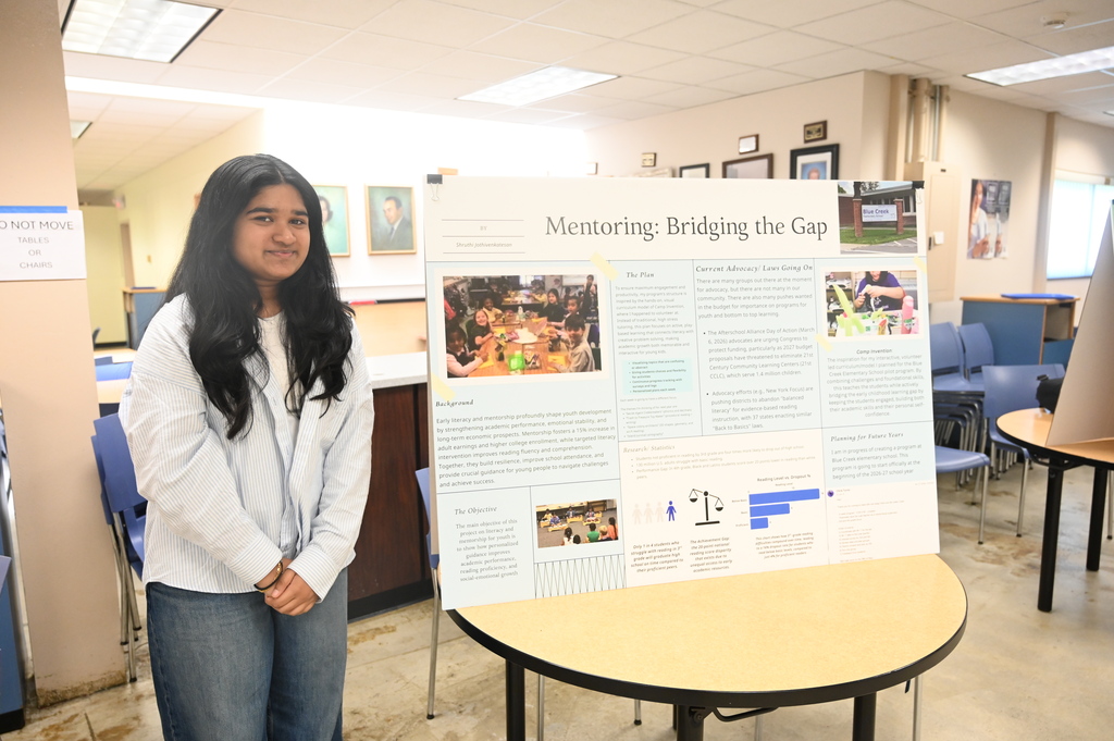 student posing with a sign stating mentoring bridging the gap