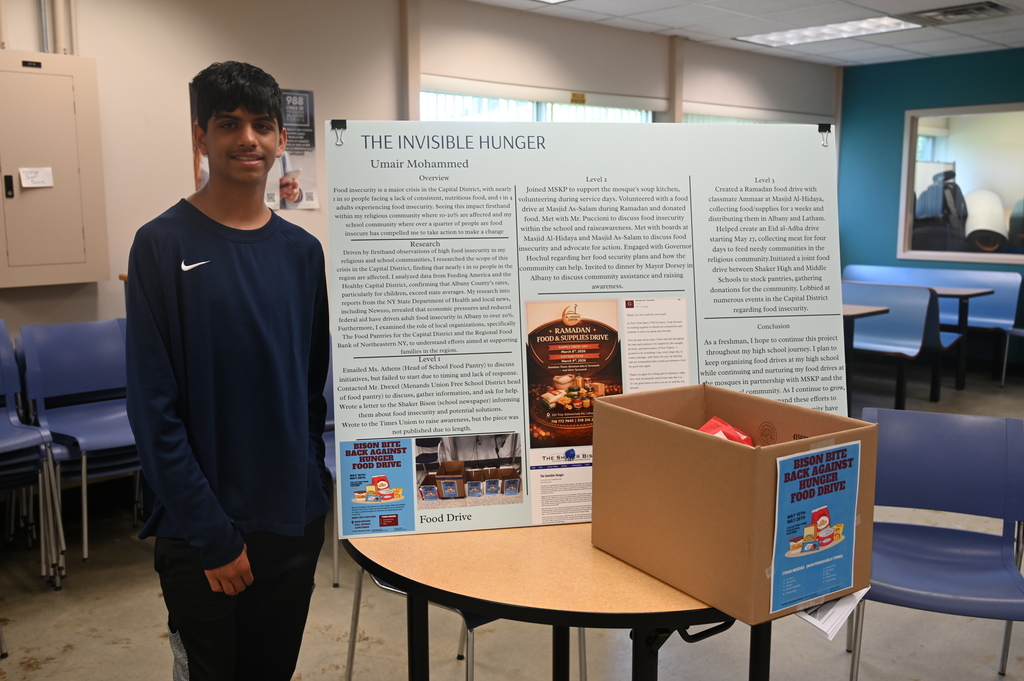 student posing with a sign stating the invisible hunger