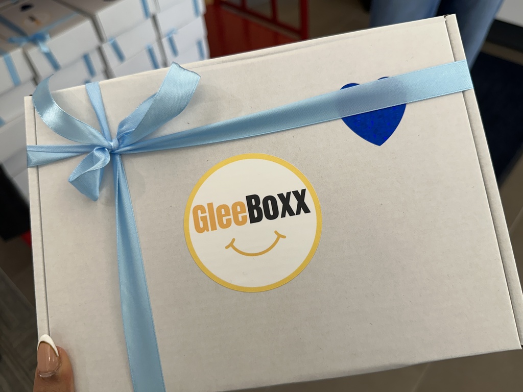 A close up of a GleeBoxx with blue ribbon and a blue heart sticker on it.