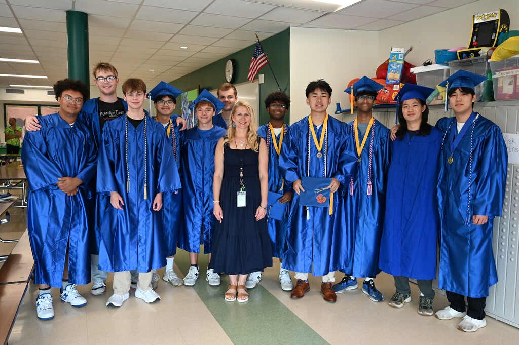 A teacher poses with a group of her former students who are graduating seniors.
