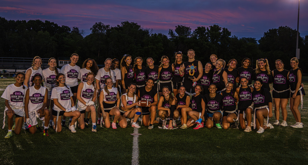 The junior and senior teams pose together after the game at sunset.