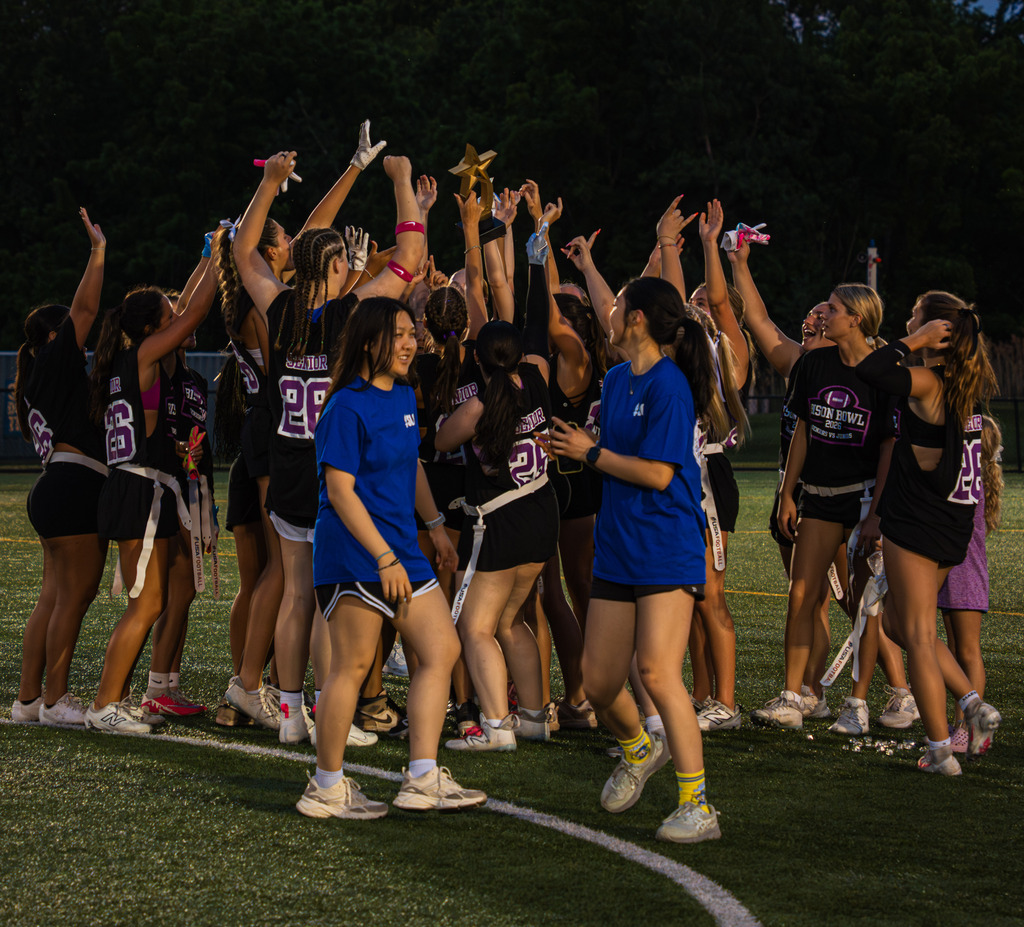 Members of the senior team hold up the trophy and celebrate around it.