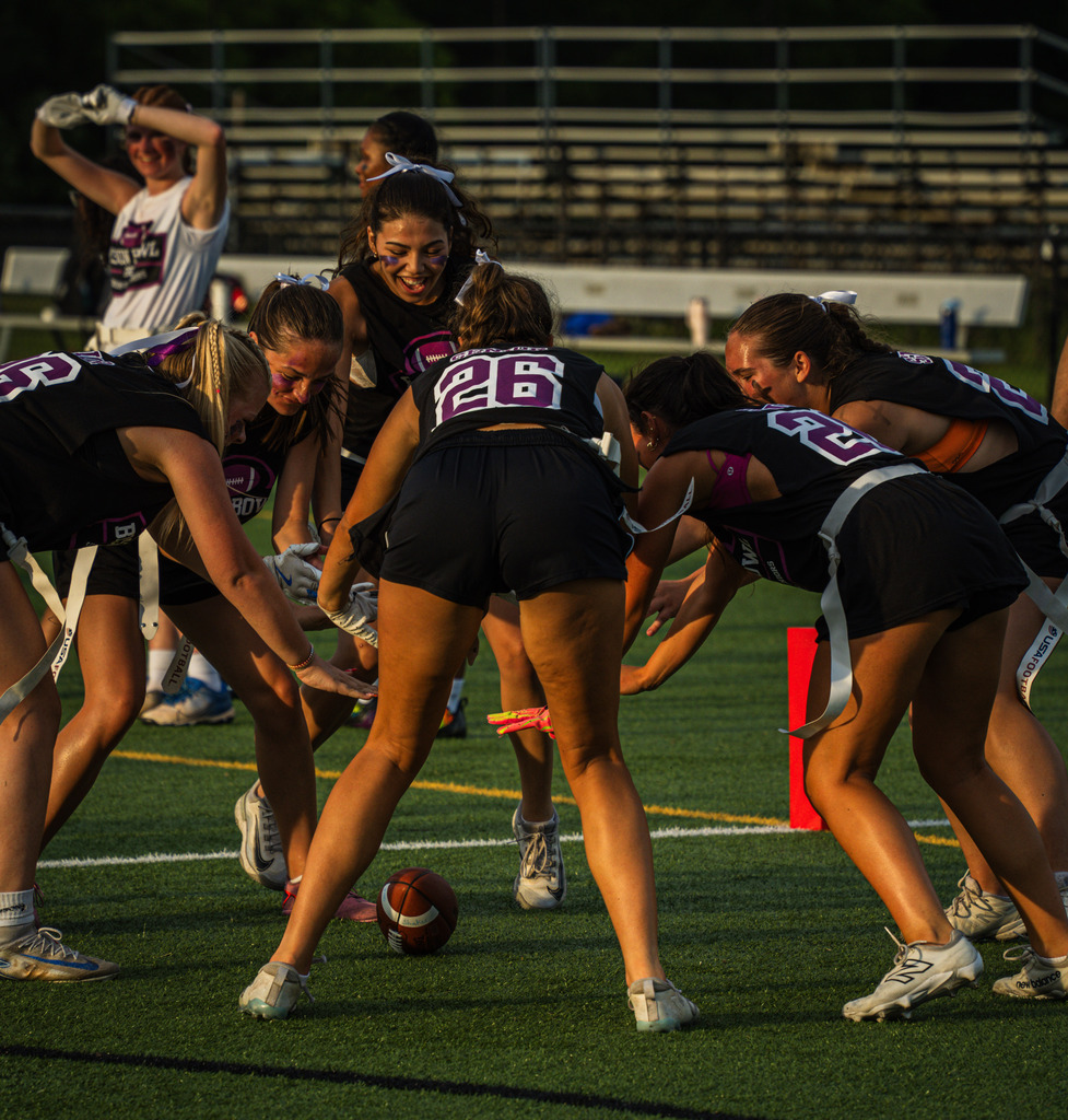 Members of the seniors celebrate around the football on the ground.