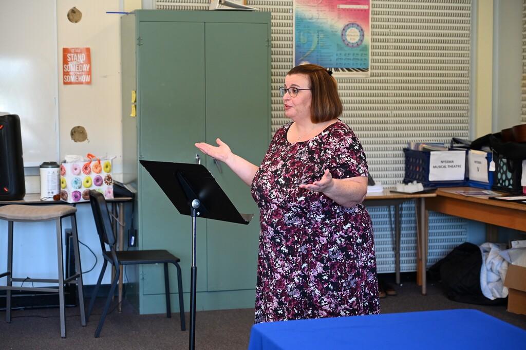 The Friends of Music President, Michelle Cannistraci, speaks at the front of the room.